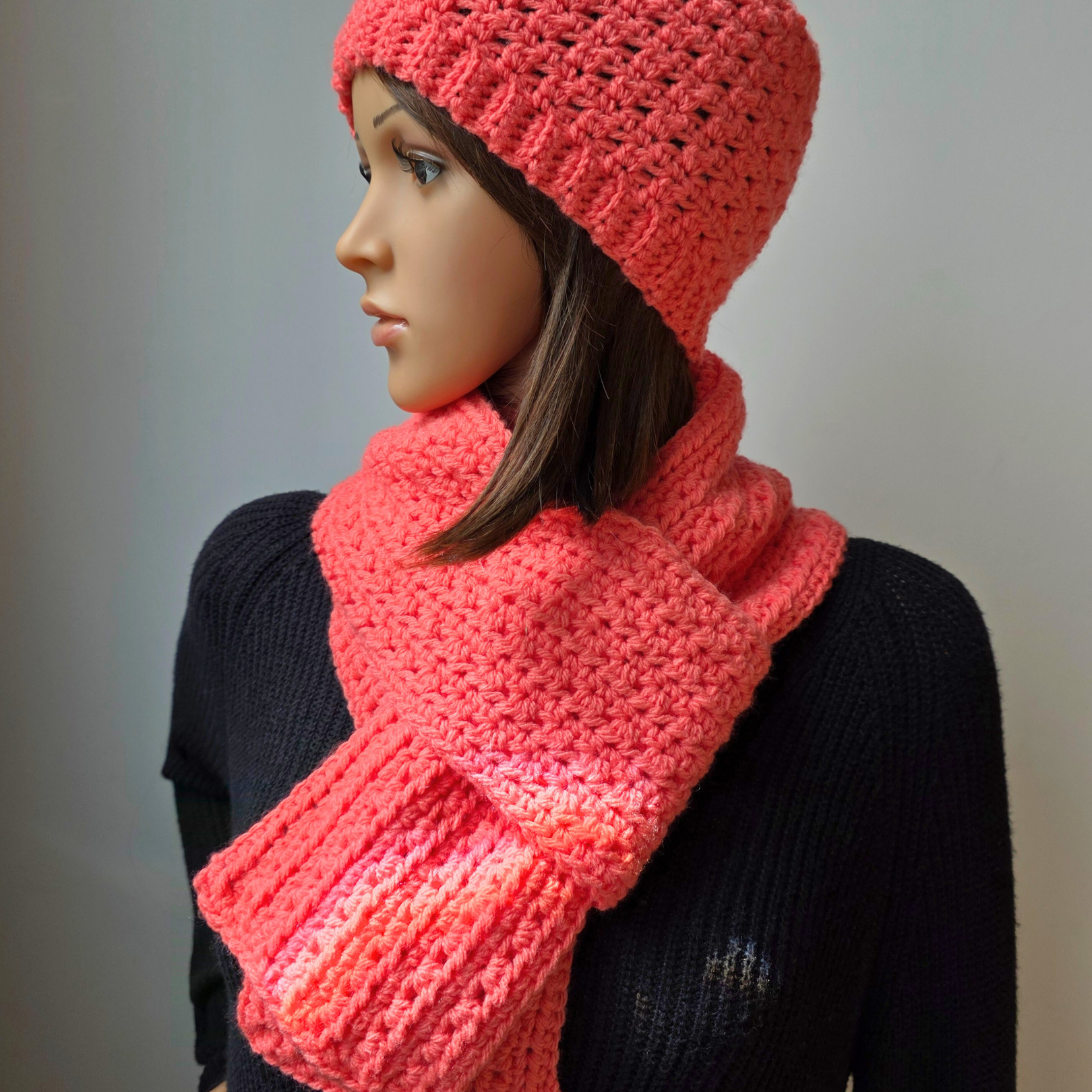 Mannequin wearing handmade Coral Wander Scarf and Hat set crocheted with coral worsted weight yarn.